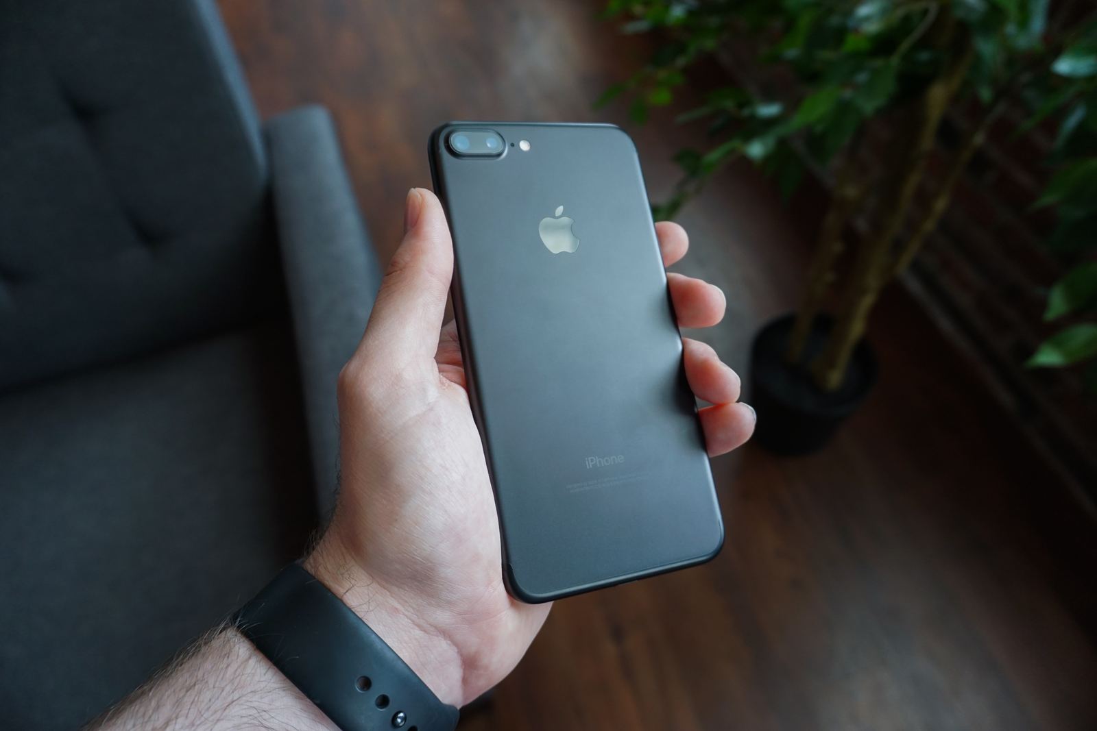 A hand holding a black smartphone outdoors